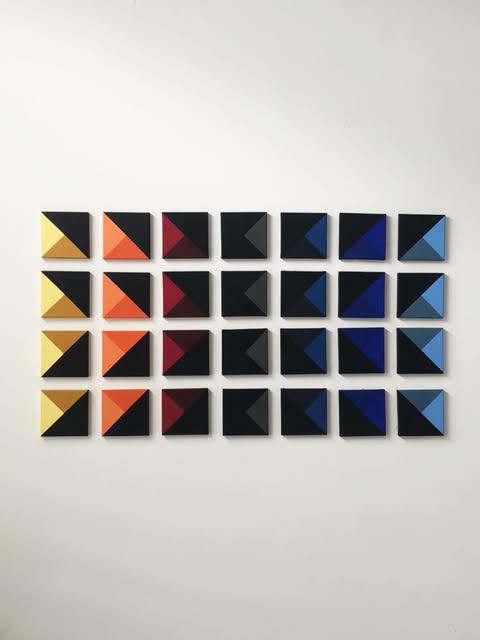 Spectrum Grid: 28 hand-built pyramids moving from yellow to blue on a white wall